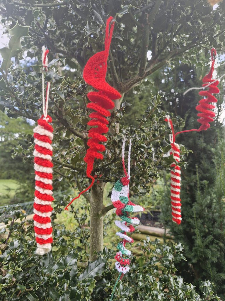 Crocheted red, white and green spiral icicle ornaments hanging in a tree