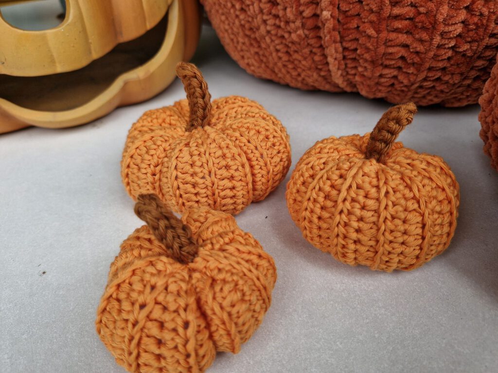 Three small orange cotton crochet pumpkins with brown stems and ribs from half double crochet in the back loop