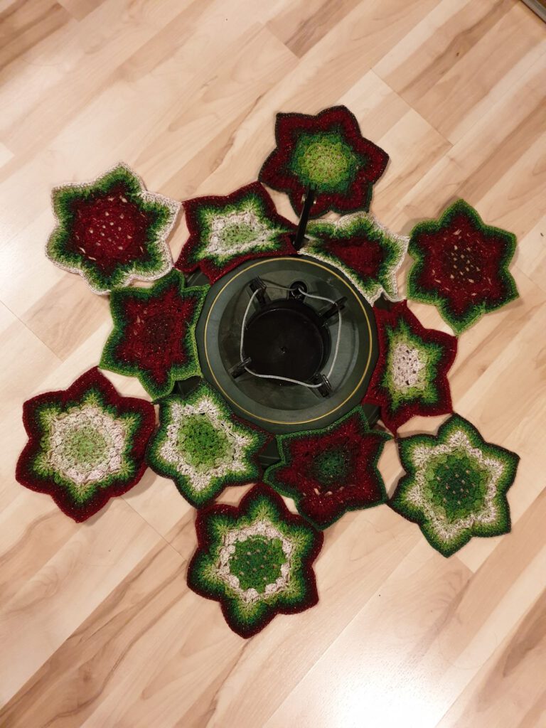 Twelve crochet hexie stars joined as you go in a ring around a Christmas tree stand