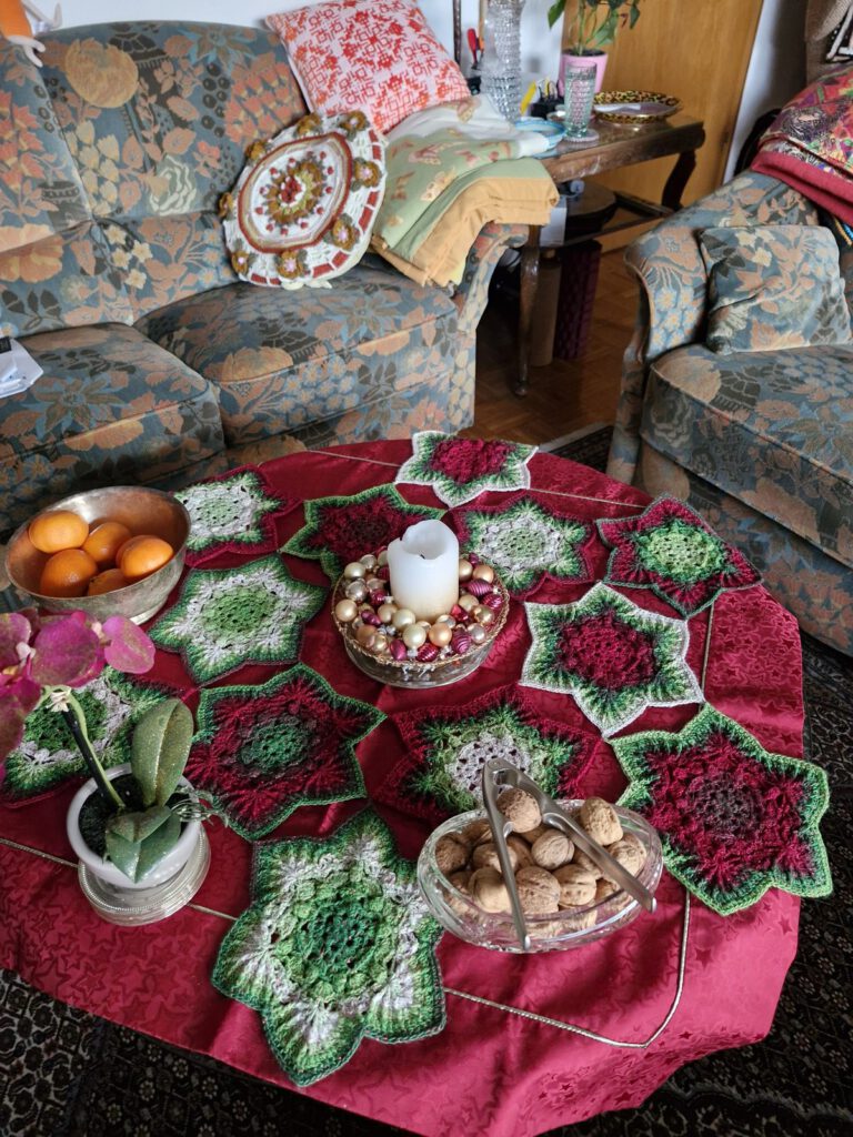 Crochet tree skirt used as a festive Christmas table cover with a candle, oranges and nuts