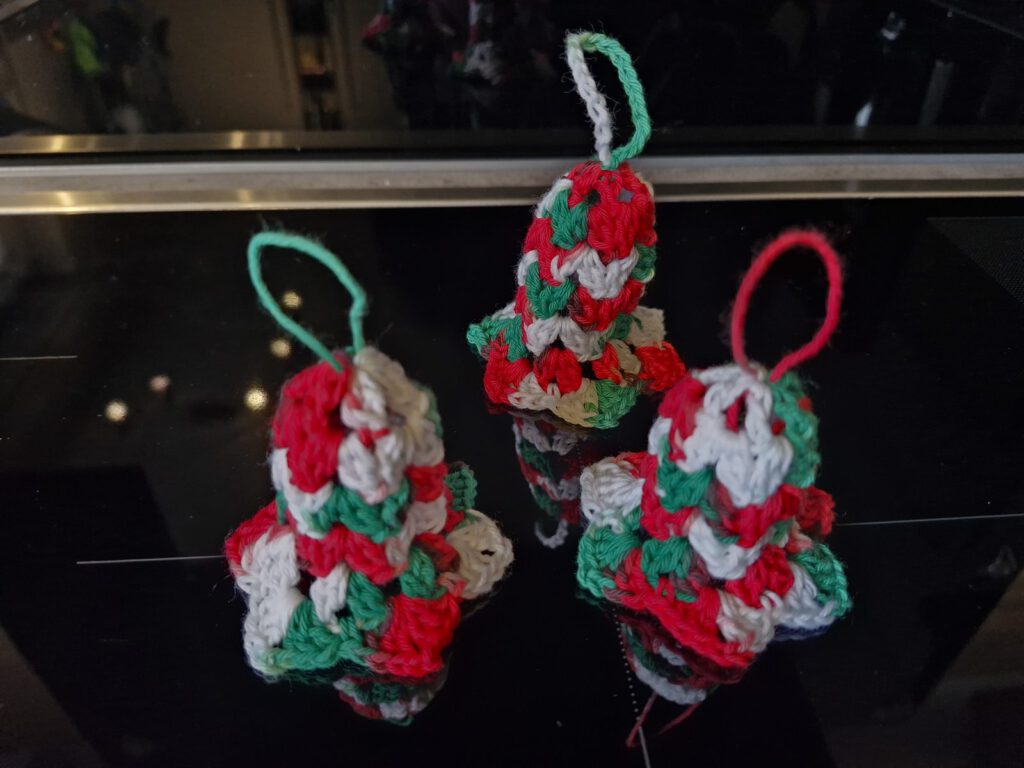 Three crocheted Christmas bells in red, green and white with hanging loops